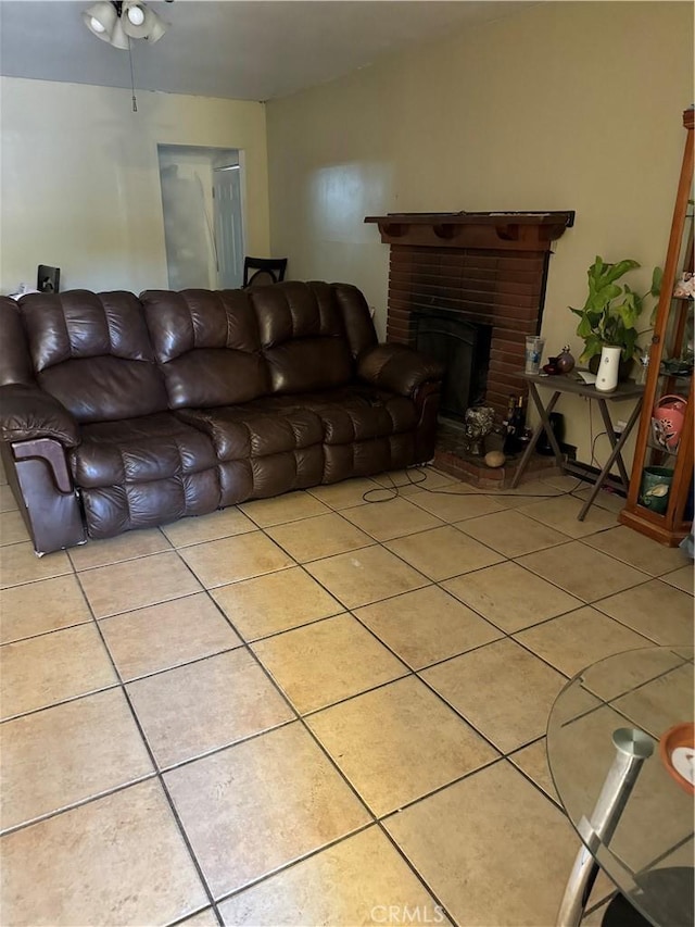 living room featuring ceiling fan, a fireplace, and light tile patterned flooring