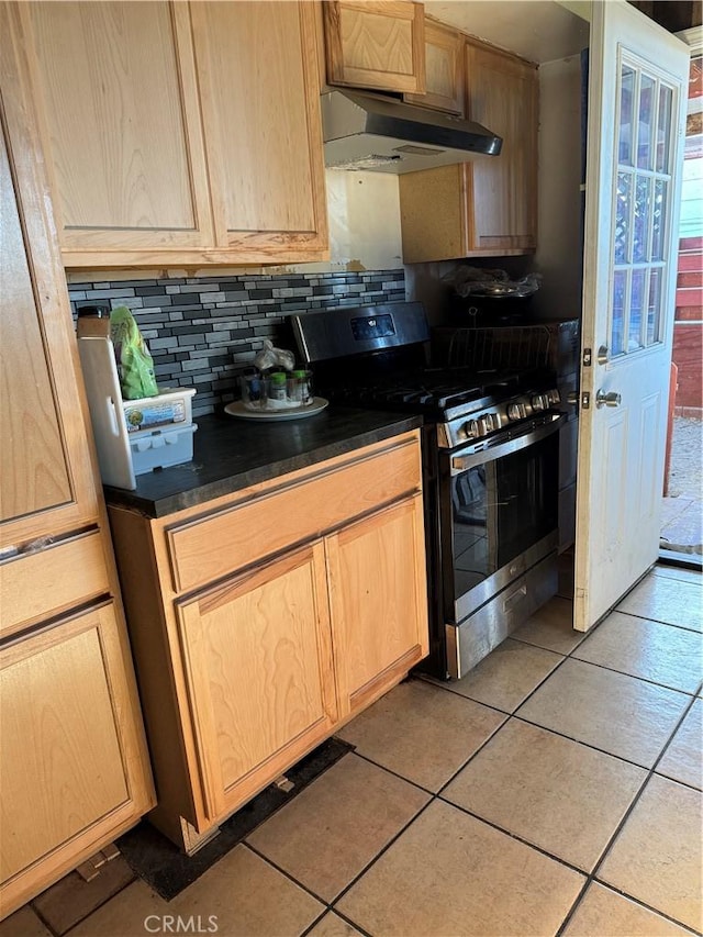 kitchen featuring stainless steel gas range, light tile patterned flooring, decorative backsplash, and light brown cabinetry