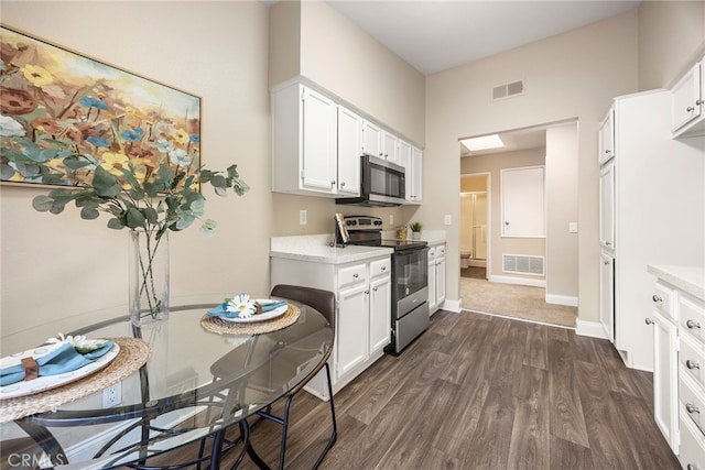 kitchen with appliances with stainless steel finishes, dark wood-type flooring, and white cabinetry