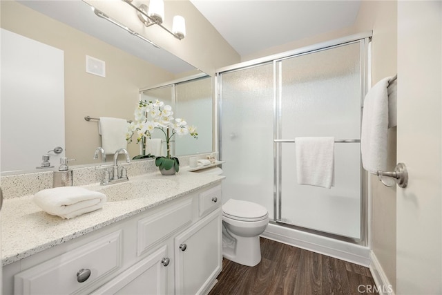 bathroom with vanity, a shower with shower door, hardwood / wood-style floors, and toilet