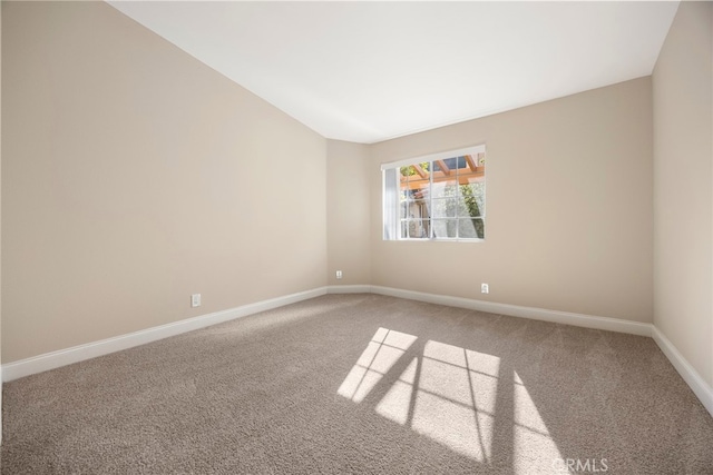 carpeted spare room with vaulted ceiling