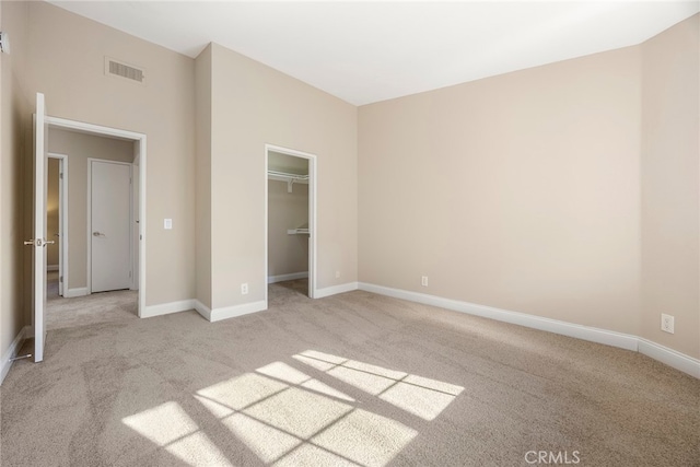 unfurnished bedroom with light colored carpet, a closet, and a spacious closet