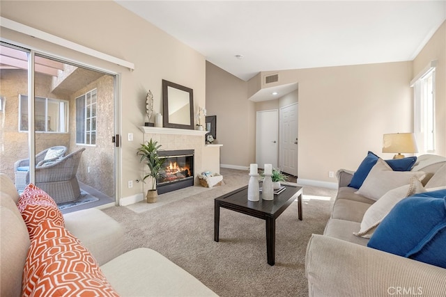 carpeted living room with vaulted ceiling, a tile fireplace, and plenty of natural light