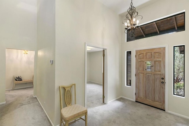 entryway with an inviting chandelier, a towering ceiling, and light carpet