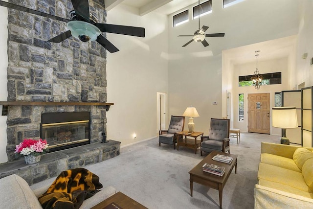 carpeted living room featuring a high ceiling, ceiling fan with notable chandelier, and a fireplace