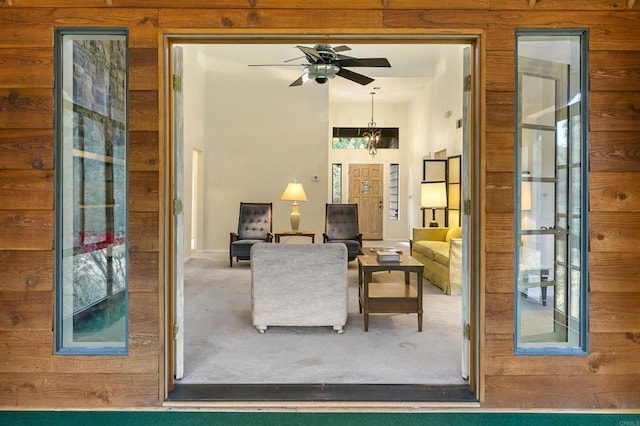 living room featuring a towering ceiling, carpet flooring, and ceiling fan with notable chandelier