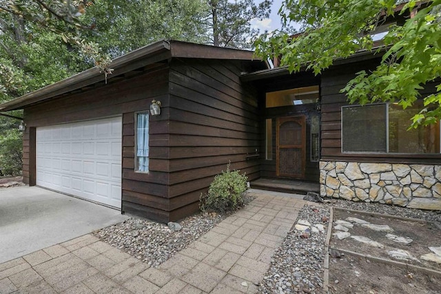 view of front of house with a garage, stone siding, and concrete driveway