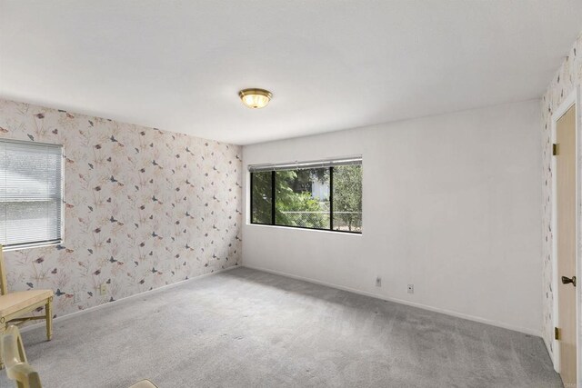 carpeted empty room with wallpapered walls and baseboards