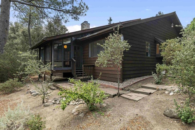 view of front of property with entry steps, a chimney, and a sunroom