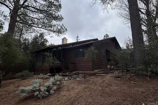 back of property featuring a sunroom and a chimney