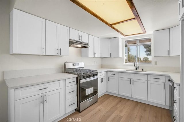 6818 El Sol Ave Unit 29, Palms, CA 92277 - kitchen featuring stainless steel appliances, under cabinet range hood, white cabinetry, and light wood-type flooring