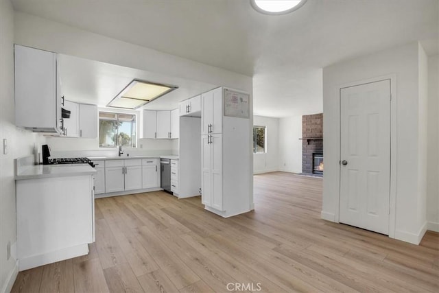 6818 El Sol Ave Unit 29, Palms, CA 92277 - kitchen featuring stainless steel dishwasher, open floor plan, light wood finished floors, white cabinets, and light countertops
