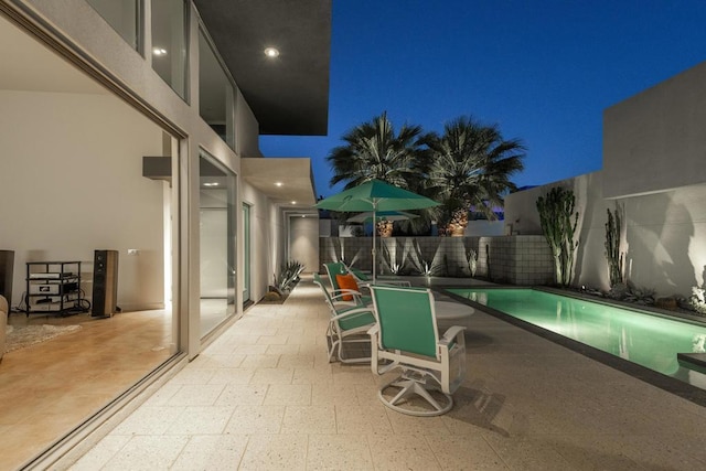 patio at twilight featuring a fenced in pool