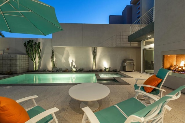 view of pool with exterior fireplace and a patio