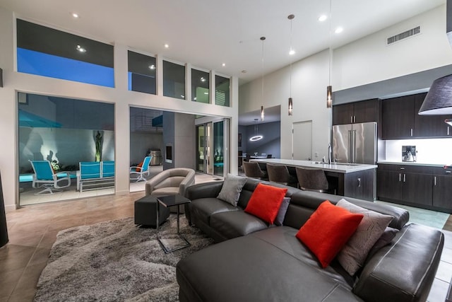 tiled living room with sink and a high ceiling