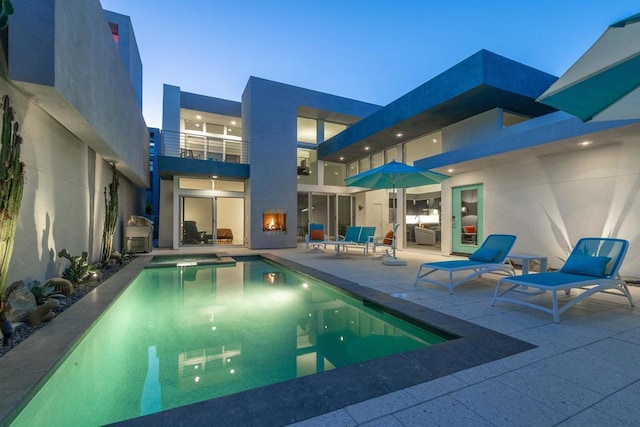 pool at dusk featuring a patio area