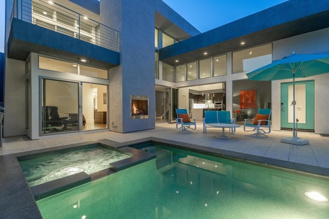 exterior space featuring a pool with hot tub, exterior fireplace, and a patio area