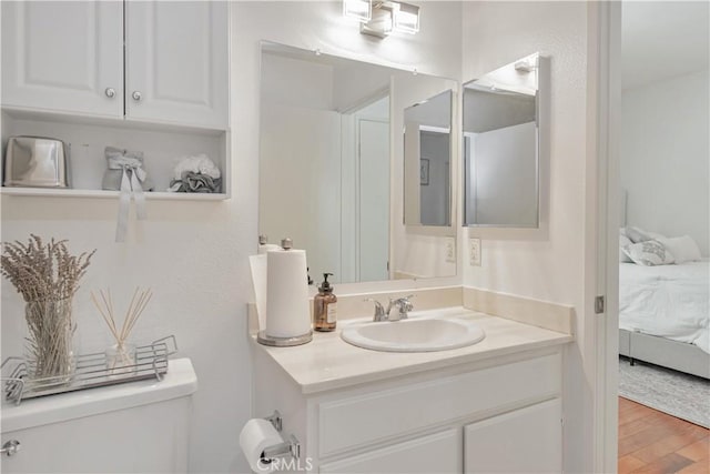 bathroom featuring wood finished floors, vanity, toilet, and ensuite bathroom