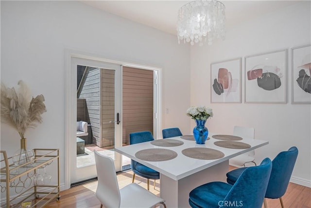 dining space featuring light wood-style floors, baseboards, and a notable chandelier