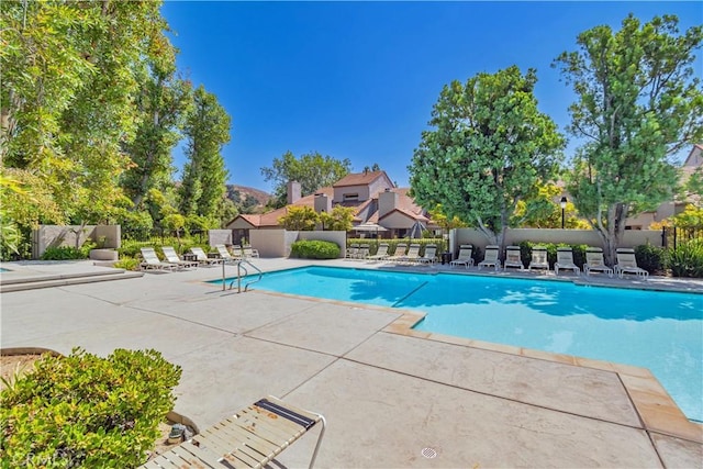 community pool with a patio area and fence