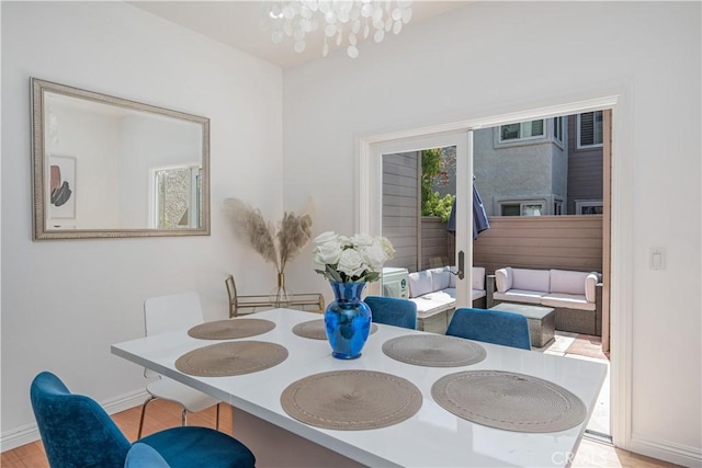 dining area featuring a notable chandelier, light wood-style flooring, and baseboards