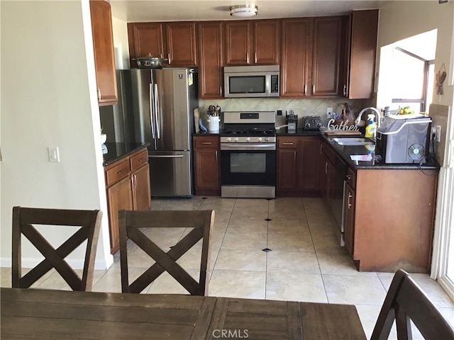 kitchen featuring tasteful backsplash, sink, light tile patterned flooring, and appliances with stainless steel finishes