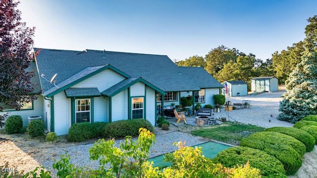 rear view of house featuring a patio, central AC, an outdoor fire pit, and a shed