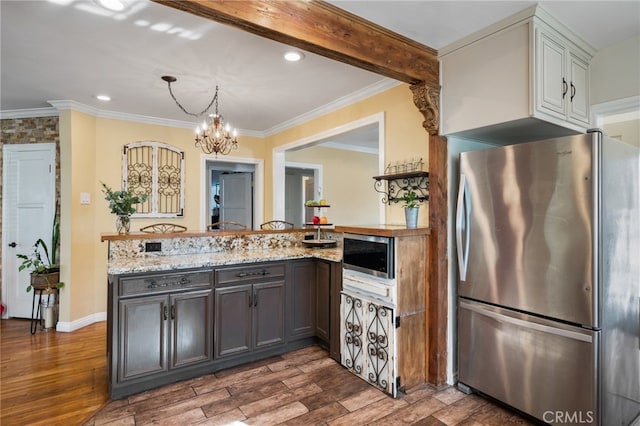 kitchen with dark wood-type flooring, stainless steel appliances, a notable chandelier, light stone countertops, and crown molding