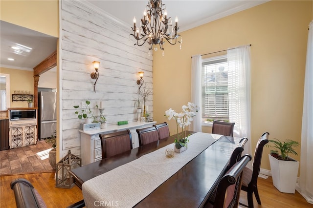 dining room featuring a notable chandelier, ornamental molding, and light hardwood / wood-style flooring