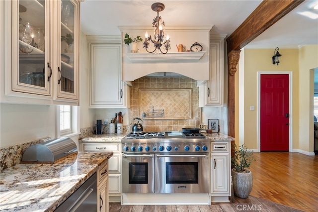 kitchen featuring double oven range, hanging light fixtures, hardwood / wood-style flooring, and light stone counters