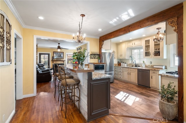 kitchen with appliances with stainless steel finishes, decorative light fixtures, a center island, and dark hardwood / wood-style flooring