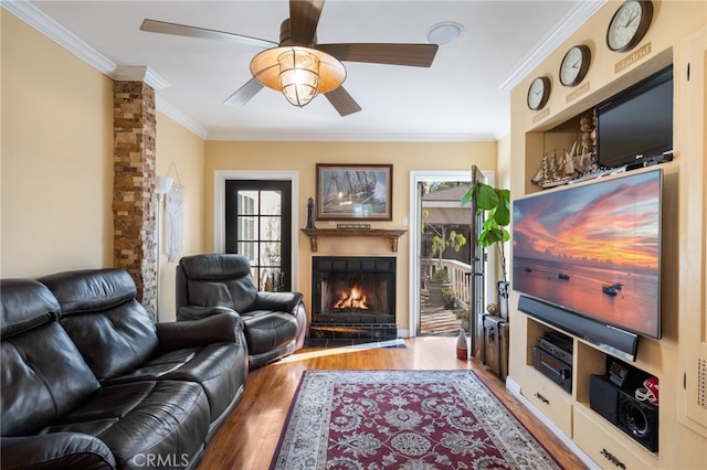 living room with wood-type flooring, ornamental molding, and ceiling fan