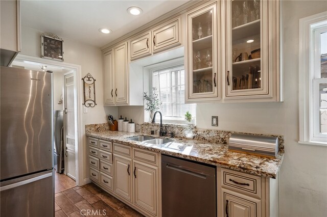 kitchen with light stone countertops, dark hardwood / wood-style floors, stainless steel appliances, sink, and cream cabinets