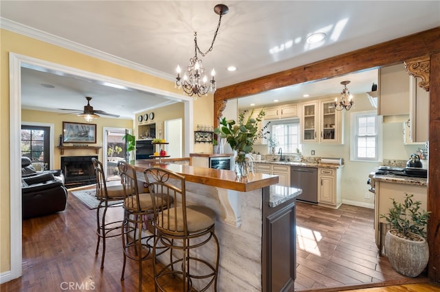 kitchen with cream cabinets, decorative light fixtures, dark hardwood / wood-style floors, and stainless steel dishwasher