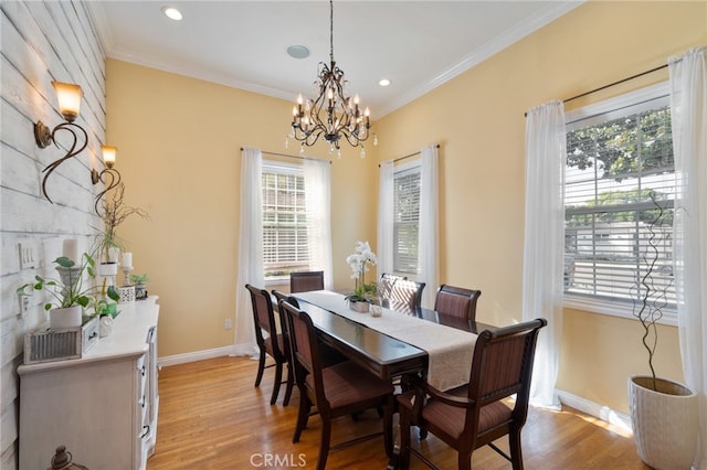 dining area featuring ornamental molding, light wood-type flooring, and an inviting chandelier