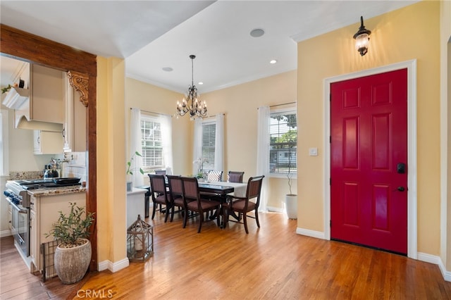 dining space with a notable chandelier, light hardwood / wood-style flooring, and crown molding