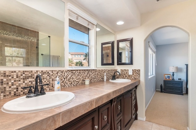 bathroom featuring backsplash, a shower, vanity, and tile patterned floors