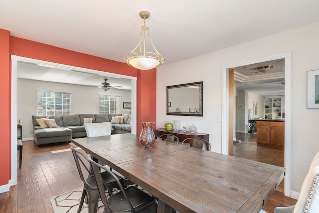 dining area with ceiling fan, ornamental molding, and dark wood-type flooring