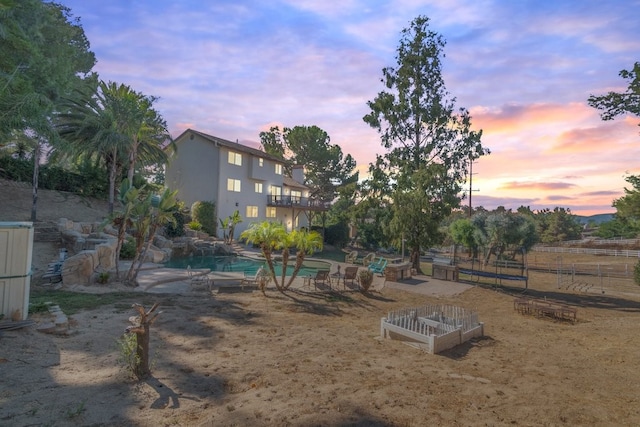 yard at dusk with a balcony, a fenced in pool, and a patio