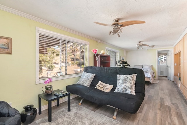 living room featuring a textured ceiling, ceiling fan, hardwood / wood-style flooring, and crown molding