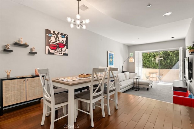 dining area featuring dark wood-type flooring and an inviting chandelier