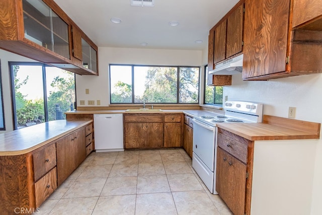 kitchen featuring white appliances, kitchen peninsula, light tile patterned floors, and sink