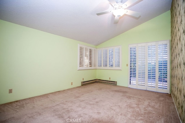 carpeted empty room featuring vaulted ceiling, ceiling fan, a baseboard heating unit, and a wealth of natural light