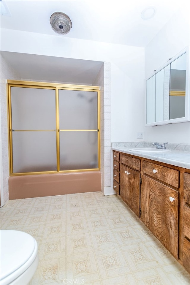 full bathroom with bath / shower combo with glass door, vanity, and toilet