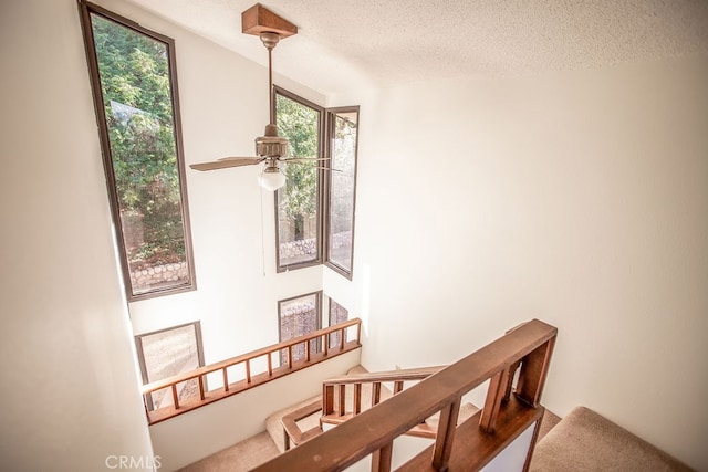 stairs featuring a textured ceiling and ceiling fan