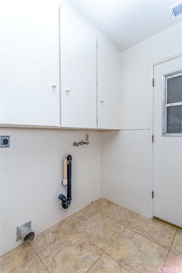 laundry room featuring cabinets, electric dryer hookup, and light tile patterned flooring