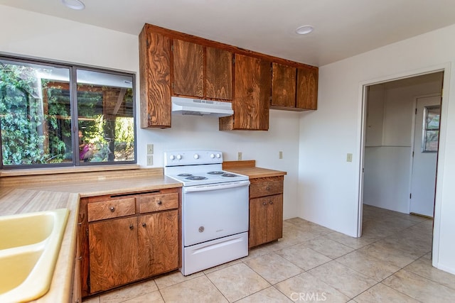 kitchen featuring sink, light tile patterned floors, and white range with electric stovetop