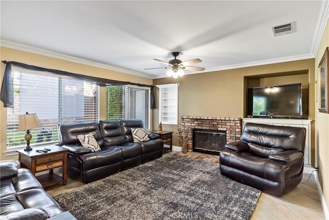 living room featuring ceiling fan, crown molding, a fireplace, and wood-type flooring