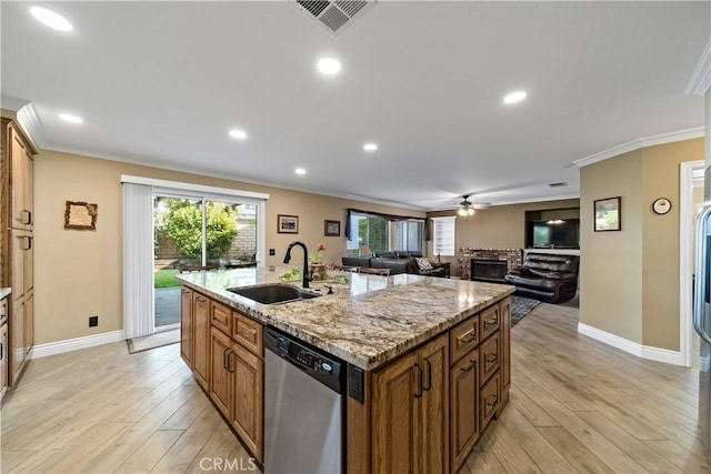 kitchen with sink, stainless steel dishwasher, light wood-type flooring, and an island with sink