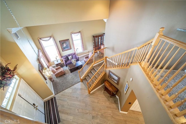 staircase featuring a towering ceiling and hardwood / wood-style floors